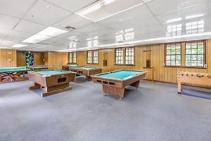 Game room with pool tables, foosball table, and wood-paneled walls.