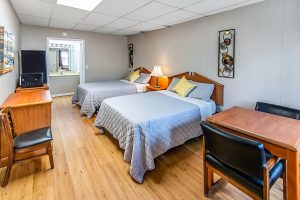 two queen beds with wooden floors. Table with two black chairs