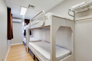 Bundick Lake RV Park Cozy narrow room at Bundick Lake Retreat and RV Park in DeRidder, Louisiana with two white bunk beds, wood floors, white walls.