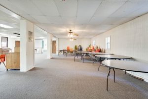 Bundick Lake RV Park Event room at Bundick Lake Retreat and RV Park in DeRidder LA with folding tables, stacked chairs, carpet, paneled walls, ceiling fans.