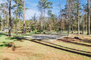 Bundick Lake RV Park Sunny park at Bundick Lake Retreat and RV Park in DeRidder LA with tall trees, picnic tables, gazebo, concrete slab, grass, tree stumps.