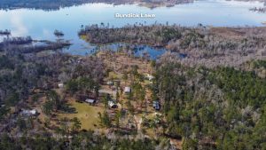 Bundick Lake RV Park Aerial view of Bundick Lake Retreat and RV Park in DeRidder, Louisiana, with forest, scattered houses, and lake shoreline.