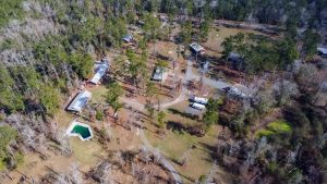 Bundick Lake RV Park Aerial view of Bundick Lake Retreat and RV Park in DeRidder, Louisiana, with RVs, cabins, pool, trees, and winding roads.