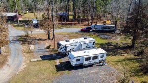 Bundick Lake RV Park Aerial view of Bundick Lake Retreat and RV Park in DeRidder, Louisiana with white RVs, vehicles, gravel lots, and scattered trees.